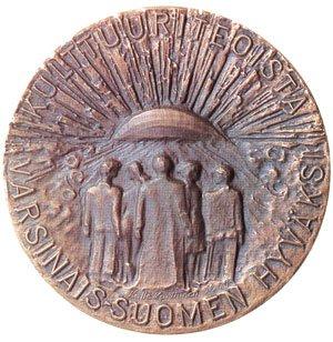 Kuvassa on pyöreä pronssinen mitali, jossa kuvattuna ihmisjoukko ja teksti kulttuuriteoista Varsinais-Suomen hyväksi