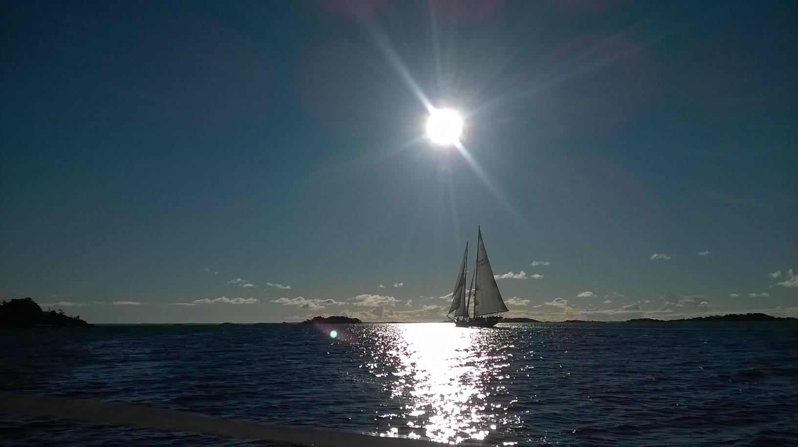 Purjevene keskellä merta, aurinko paistaa