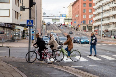 Pyöräilijät ja jalankulkija ylittävät suojatietä