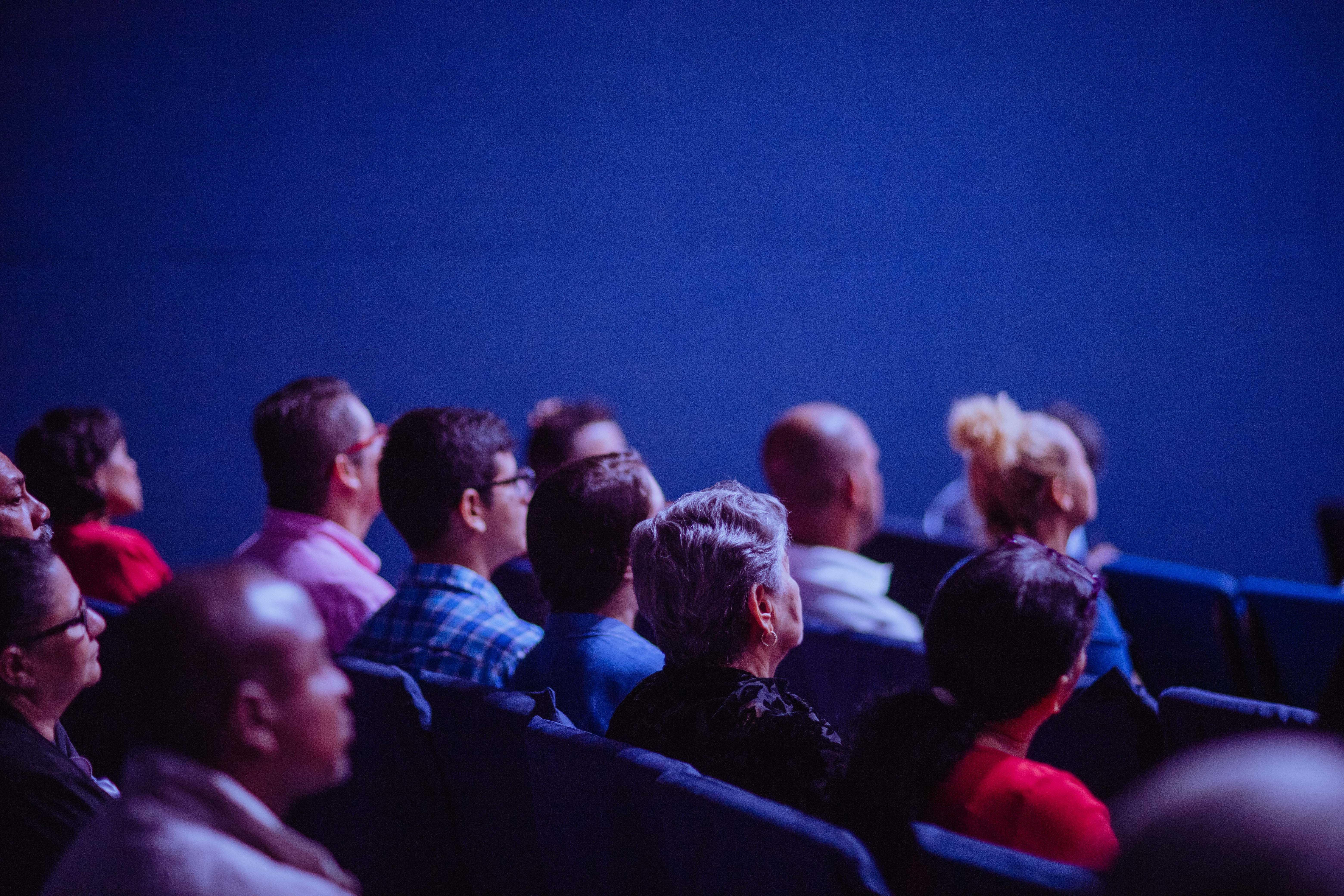 Ihmisiä auditoriossa kuuntelemassa esitystä.