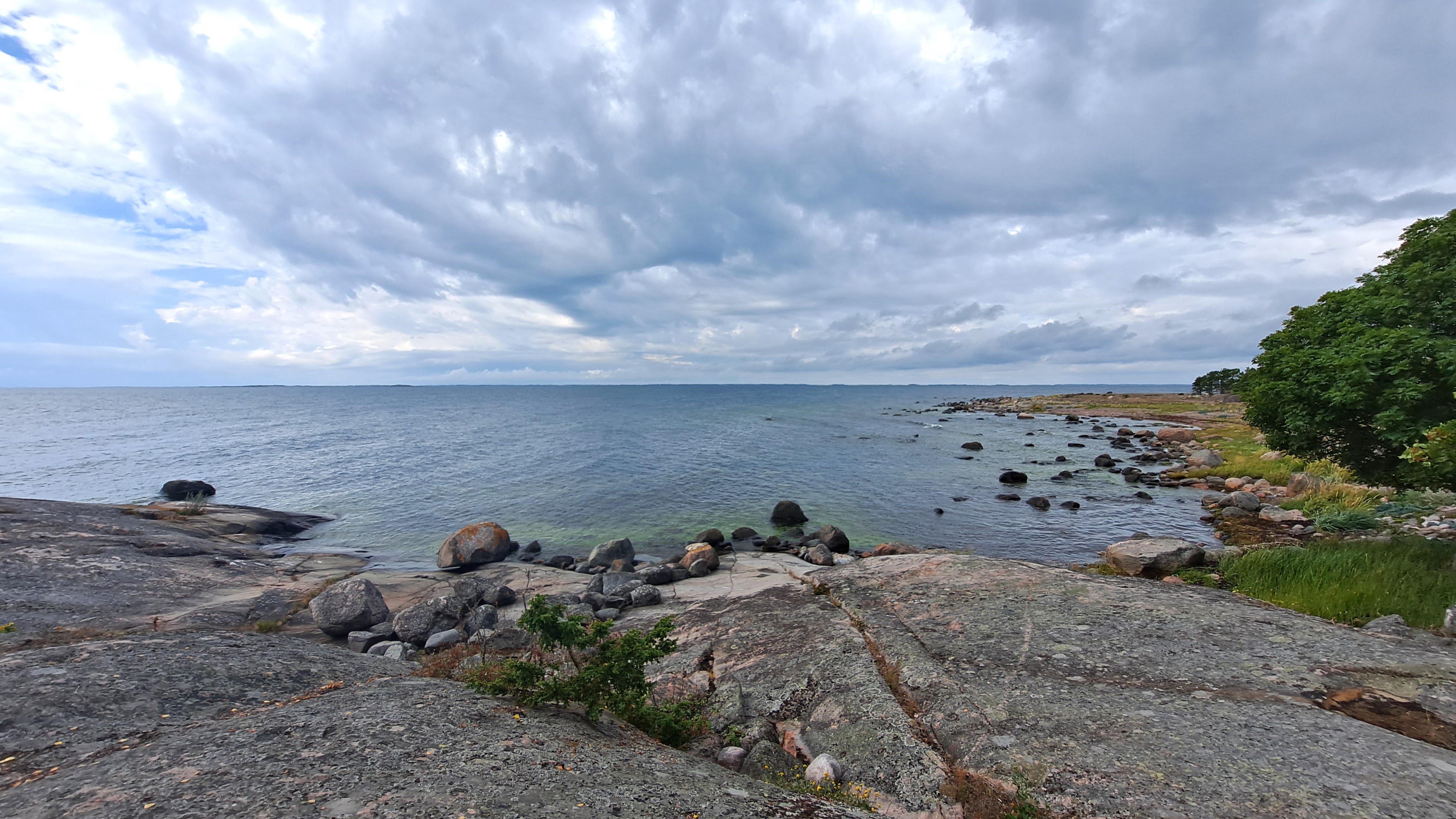 Kivistä rantamaisemaa ja merta pilvisenä päivänä.