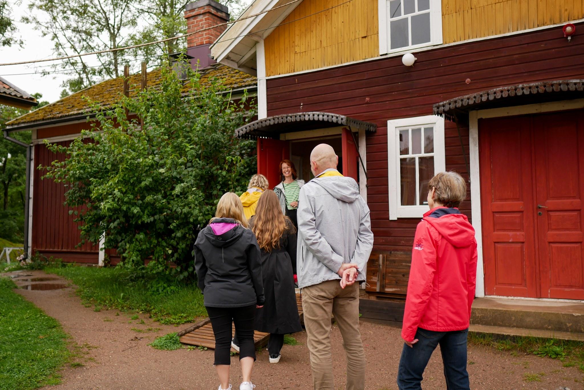 Hyväntuulisia ihmisiä jonottamassa sisään puutaloon Kuralan kylämäessä.
