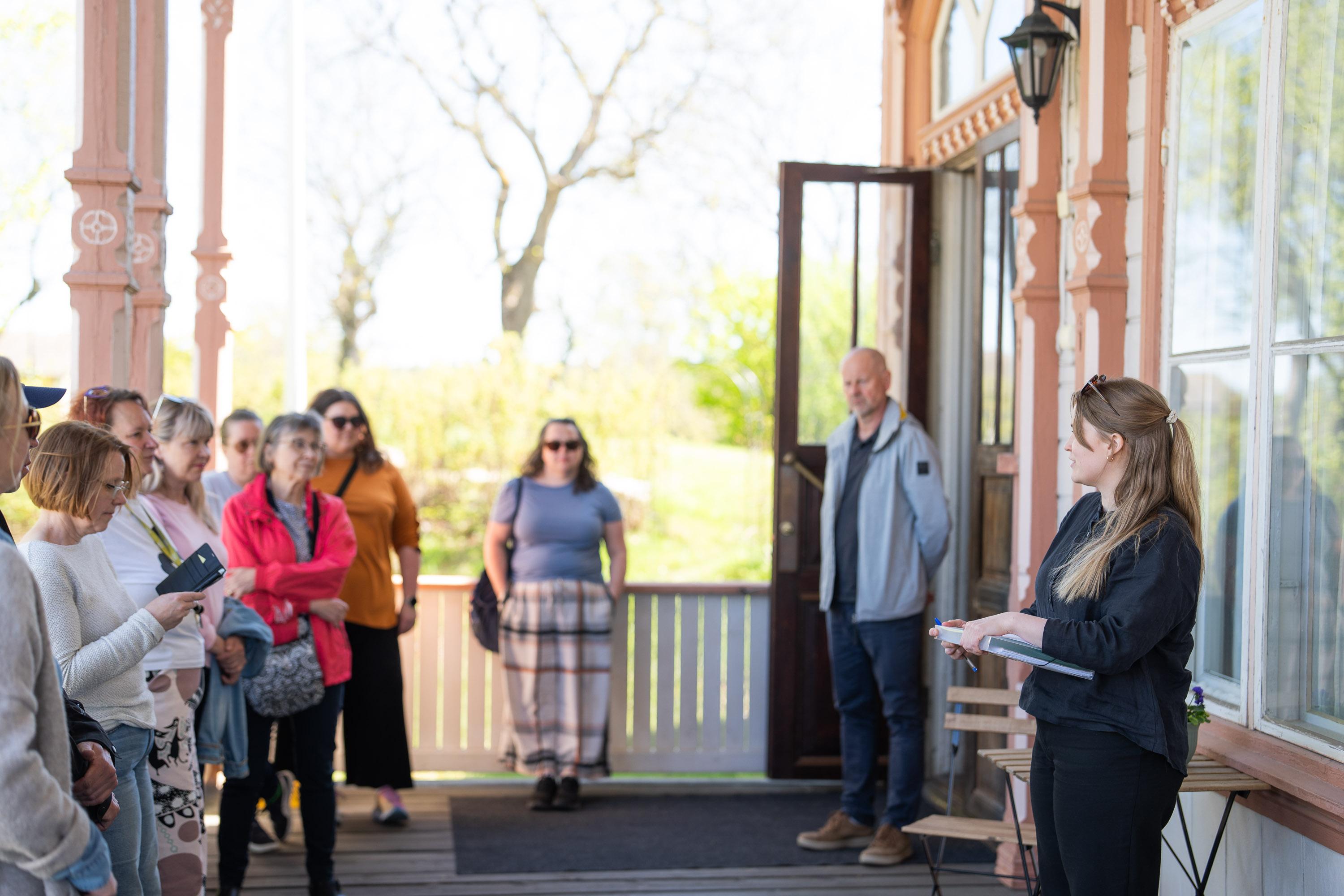 Ihmisiä terassilla kuuntelemassa puhujaa.