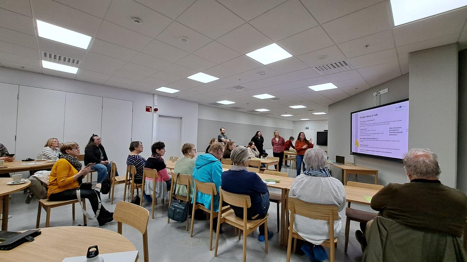 Ihmisiä katsomassa diaesitystä kokoushuoneessa.