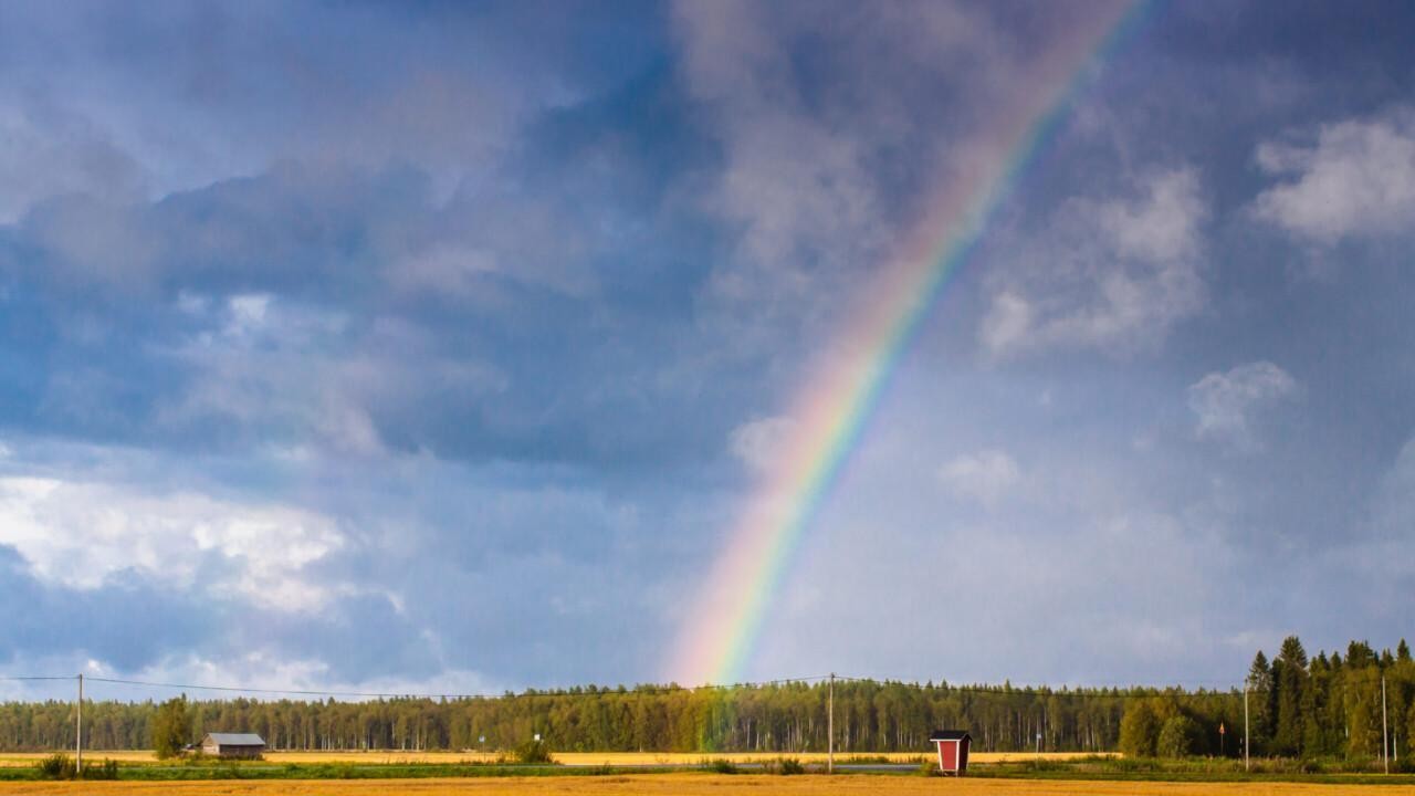 Peltomaisema ja taivas jossa sateenkaari