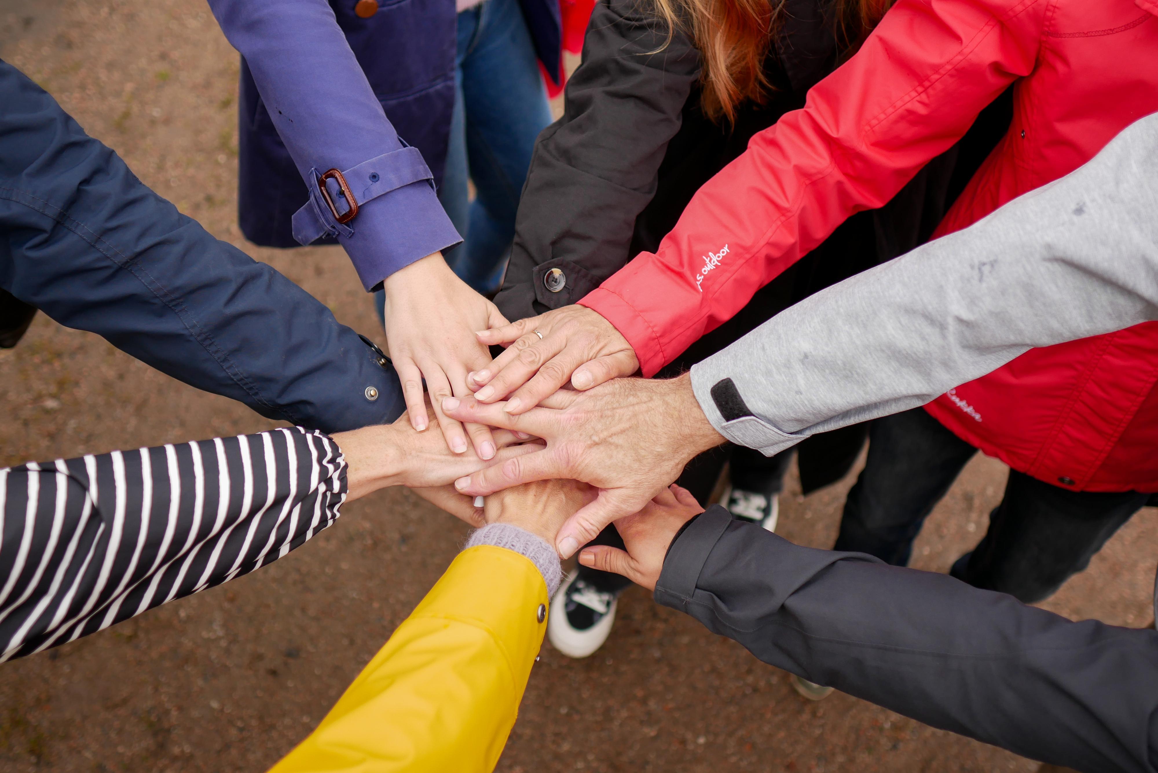 Seitsemän kättä yhdessä ringin keskellä. Värikkäitä hihoja.